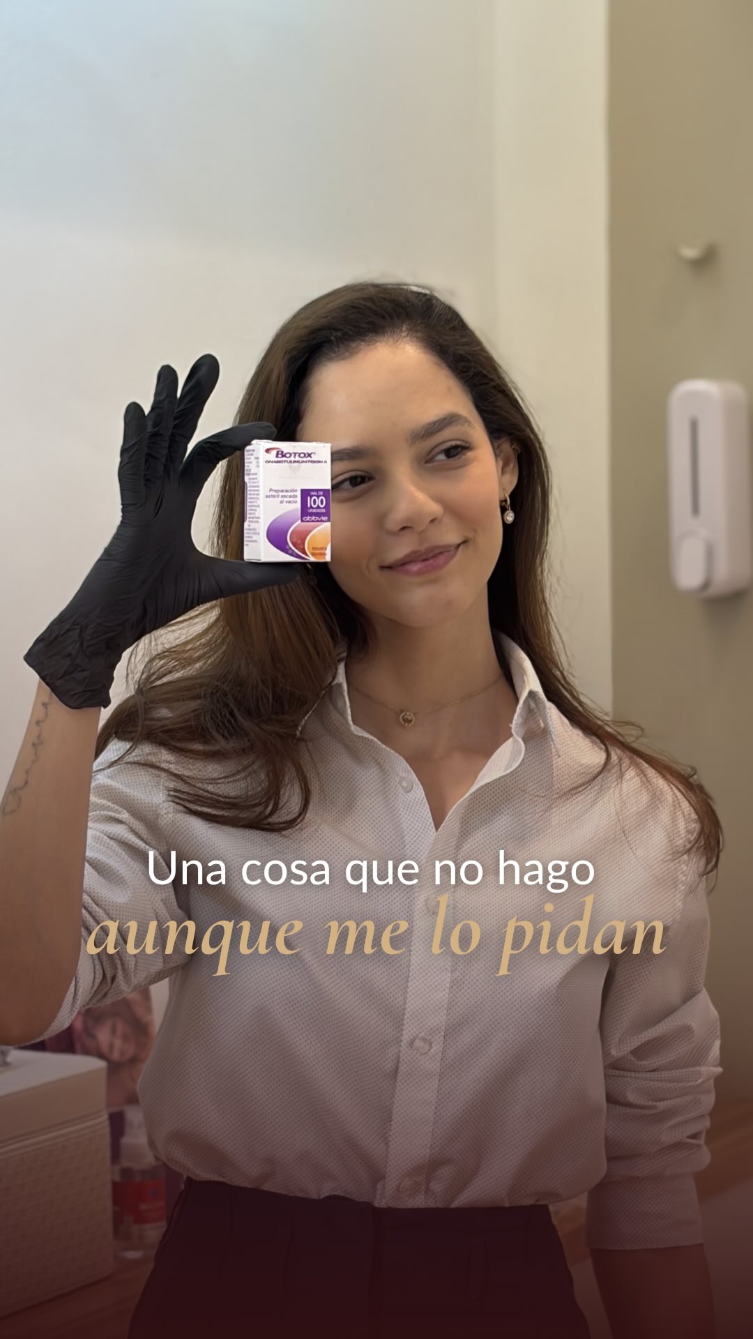 La Dra. María Eduarda Peres sonríe y sostiene con un guante negro una caja de Botox junto a su rostro