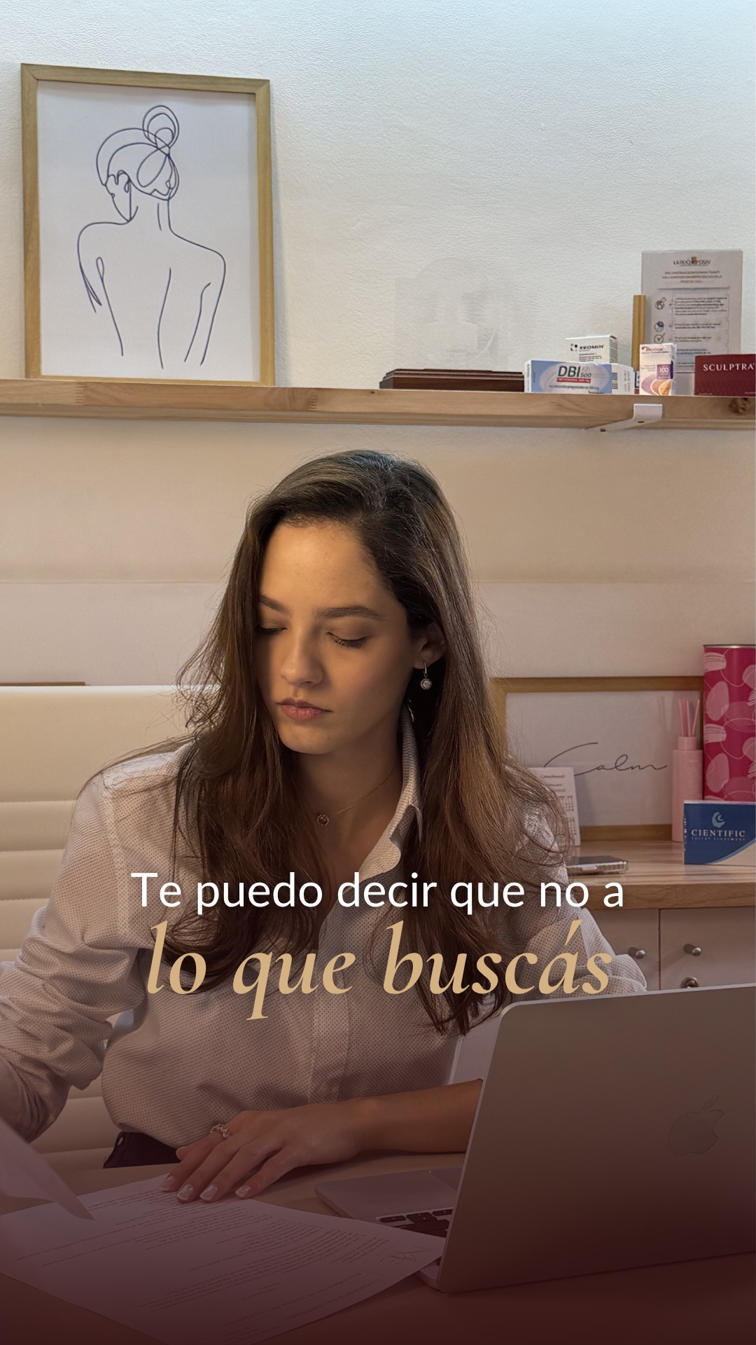 La Dra. María Eduarda Peres revisa papeles en su escritorio, bajo un cuadro de arte lineal